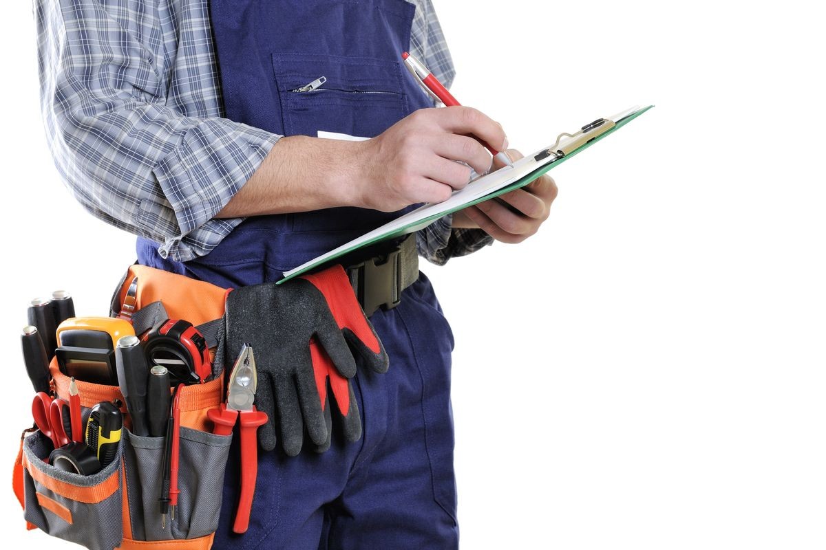 Young electrician technician takes notes on notepad, isolated on white background.